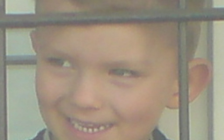 Chłopiec uśmiechający się zza krat, radosny moment.