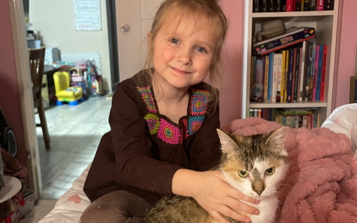 Mała dziewczynka przytulająca kota w przytulnym pokoju.