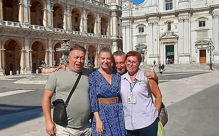 Grupa ludzi pozująca do zdjęcia na tle zabytkowego budynku.