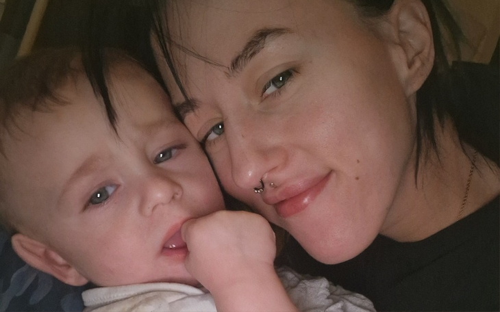 Kobieta z dzieckiem, oboje uśmiechnięci na zdjęciu.