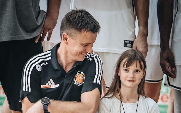 Mężczyzna i dziewczynka, oboje uśmiechnięci, w sportowej atmosferze.