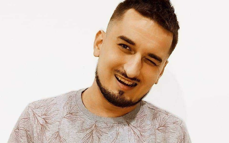 Mężczyzna z uśmiechem, pozujący do zdjęcia w casualowym stroju.