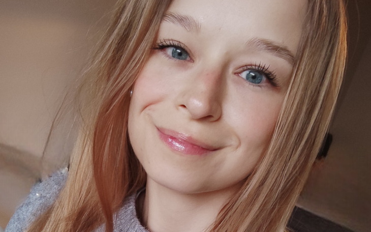 Portret uśmiechniętej dziewczyny z długimi włosami.