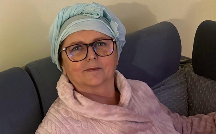 Kobieta w okularach i turbanie siedzi na kanapie.