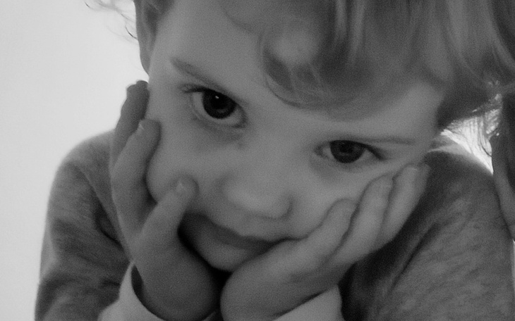 Dziecko z rękami na twarzy, wyrażające smutek.