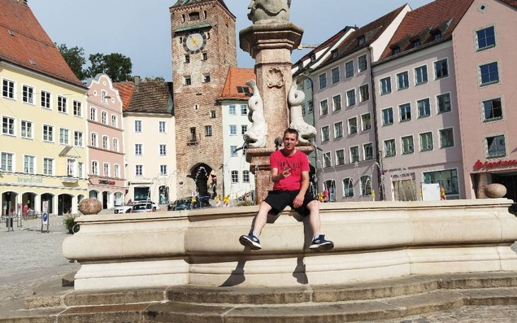 Mężczyzna siedzący na fontannie w malowniczym mieście.