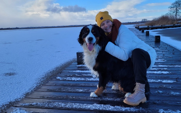 Kobieta z psem na molo, w zimowej scenerii.