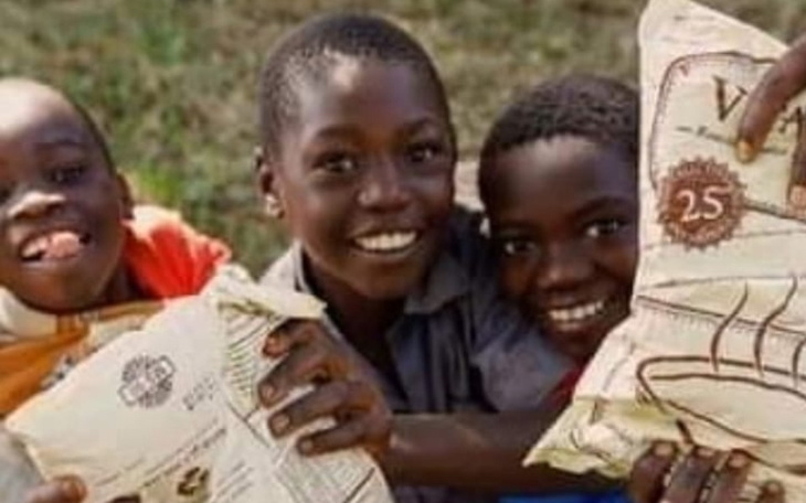 Trzech uśmiechniętych chłopców trzymających worki z jedzeniem.