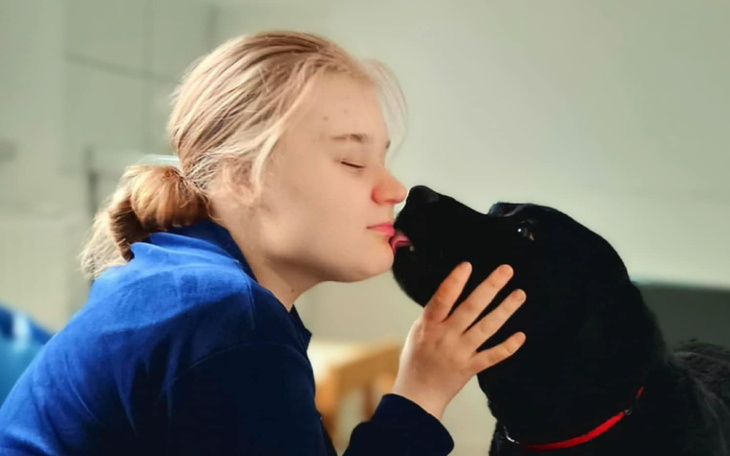 Dziewczyna całuje swojego psa, wyrażając miłość.