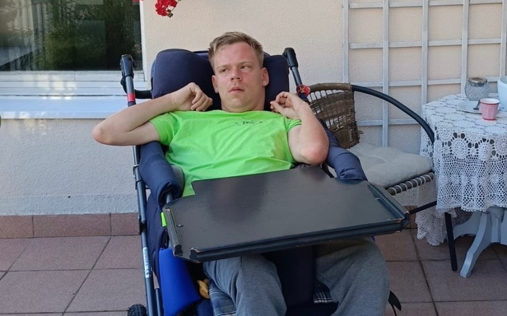 Mężczyzna w wózku inwalidzkim, siedzący na tarasie.