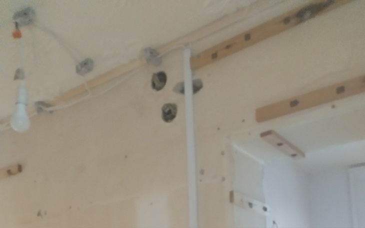 Widok na ścianę z instalacją elektryczną w trakcie remontu.
