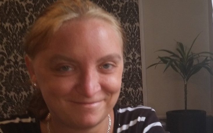 Uśmiechnięta kobieta w pomieszczeniu z rośliną.