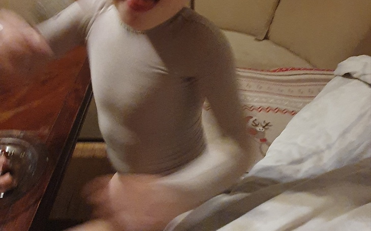 Dziecko w obcisłym ubraniu bawi się przy stole.