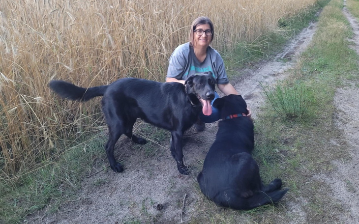 Kobieta z dwoma psami na spacerze w polu.