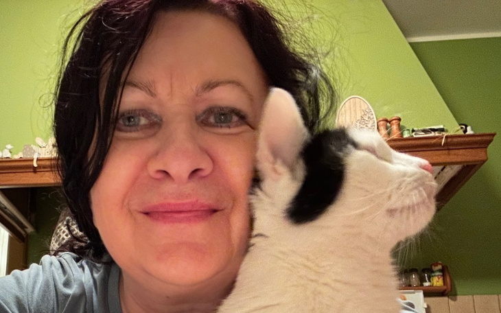Kobieta z kotem, uśmiechająca się do kamery.