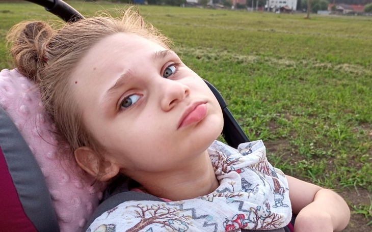 Dziewczynka w wózku spacerowym, patrzy w dal.