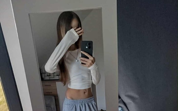 Młoda kobieta robiąca selfie w lustrze, zakrywająca twarz.