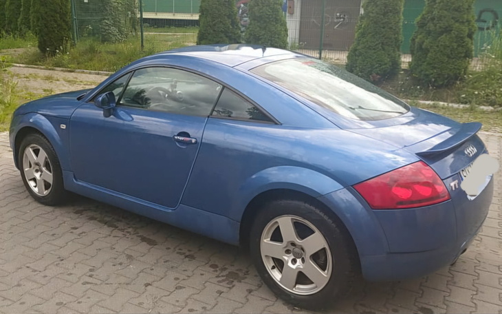 Niebieskie Audi TT zaparkowane na chodniku.