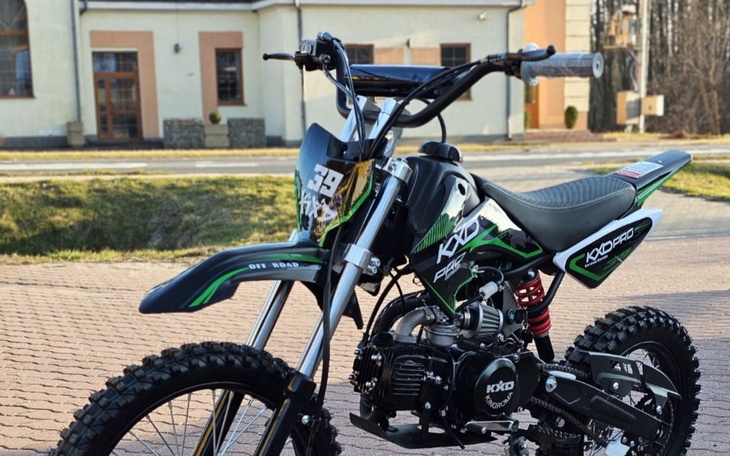 Motocykl terenowy na chodniku, w tle budynek.