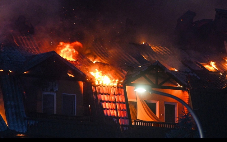 Zbliżenie na dach płonącego budynku, ogień i dym.