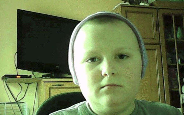 Chłopiec z czapką, siedzący przed telewizorem.