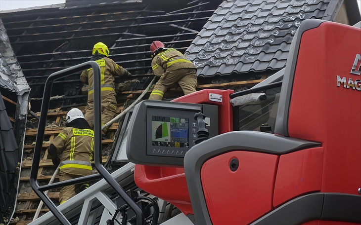 Strażacy gaszący pożar na dachu budynku.