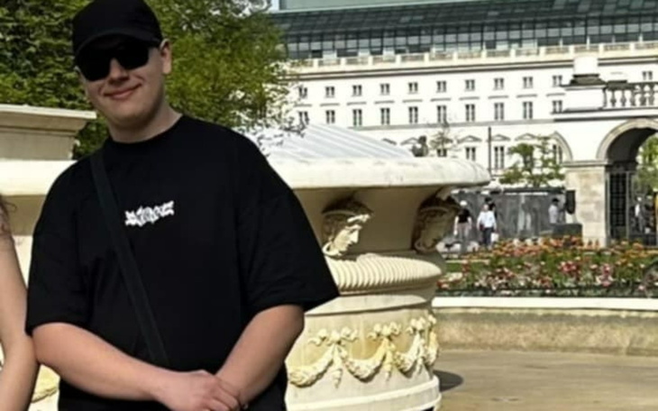 Mężczyzna w czarnej koszulce, pozujący w parku.