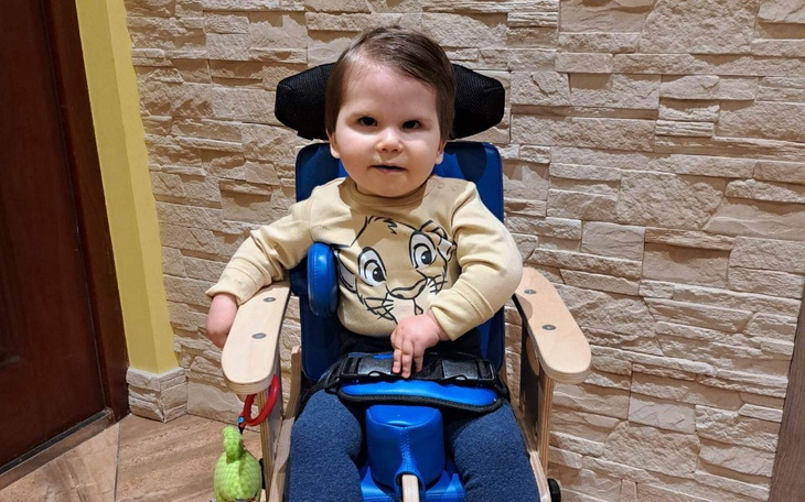 Mały chłopiec w wózku, uśmiechający się do kamery.