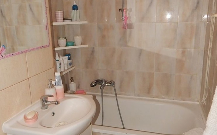 Łazienka z wanną i umywalką, z różnymi kosmetykami na półkach.