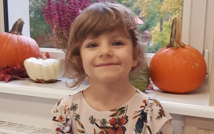 Uśmiechnięta dziewczynka w otoczeniu jesiennych dekoracji.