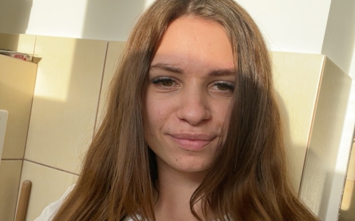 Młoda kobieta z naturalnym uśmiechem, w jasnym oświetleniu.