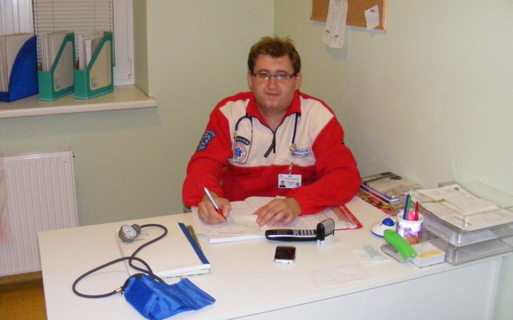 Mężczyzna w mundurze medycznym pisze notatki w biurze.