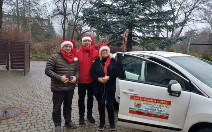 Trzej wolontariusze w świątecznych czapkach.
