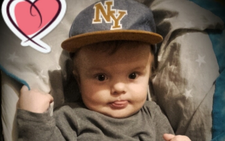 Małe dziecko w czapce, siedzące na łóżku.