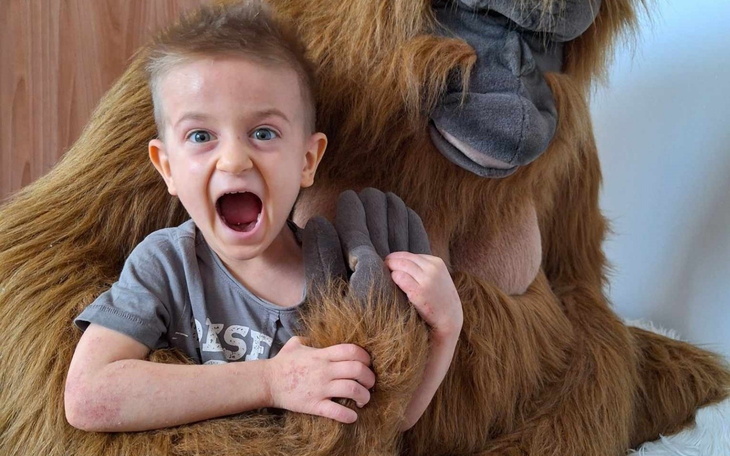 Chłopiec z uśmiechem trzymający rękę na futrze małpy.