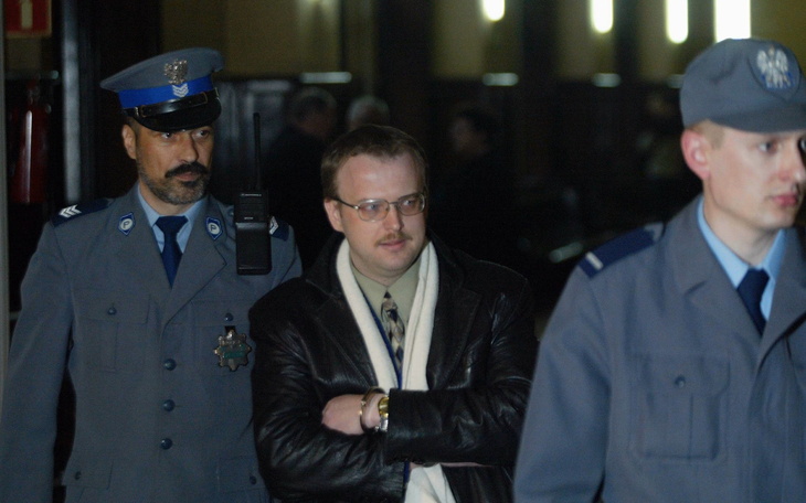 Mężczyzna eskortowany przez policję w sądzie.