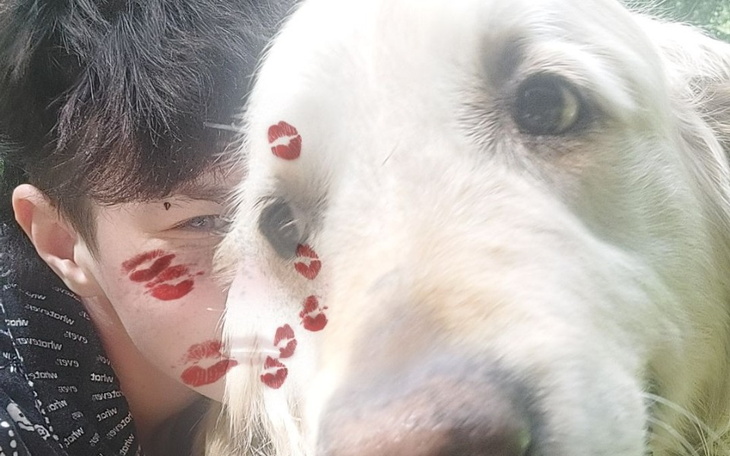 Chłopak z psem, na jego twarzy ślady pocałunków.