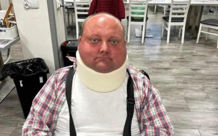 Mężczyzna w kołnierzu ortopedycznym siedzący w pomieszczeniu.