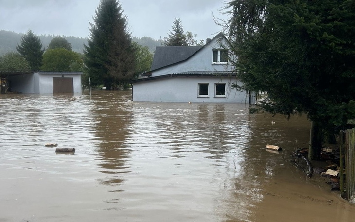 Zalany dom po powodzi, otoczenie z drzewami.
