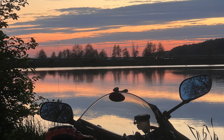 Widok na jezioro o zachodzie słońca z motocyklowym lusterkiem.