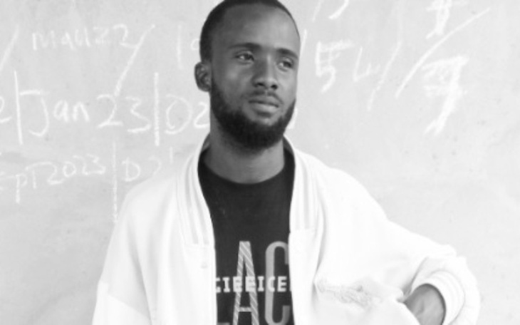 Mężczyzna w białej kurtce, pozujący na tle ściany.