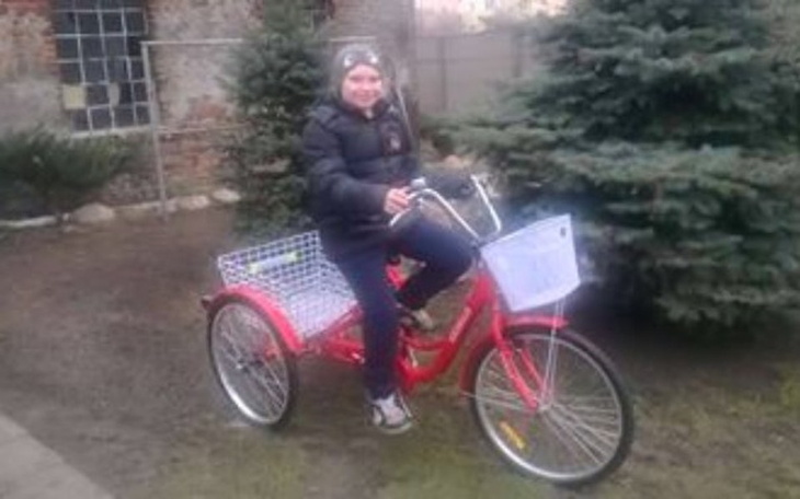 Chłopiec na rowerze trójkołowym w ogrodzie.