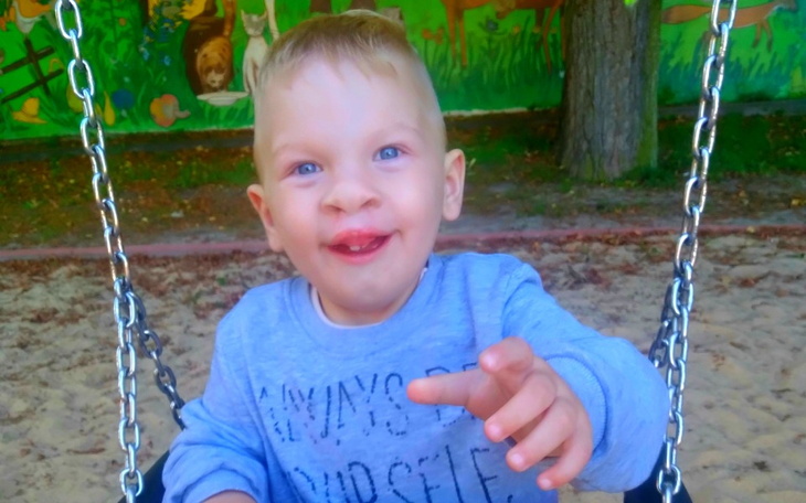 Chłopiec na huśtawce, uśmiechnięty i radosny.