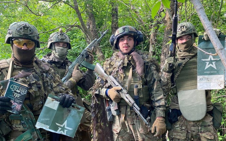 Czterech żołnierzy w mundurach, pozujących w lesie.