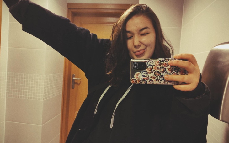 Młoda kobieta robiąca selfie w łazience z uśmiechem.