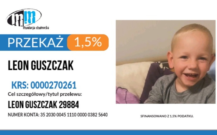 Mały chłopiec uśmiechający się do kamery na tle kolorowego plakatu.