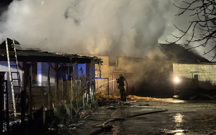 Strażak gaszący pożar w zniszczonym budynku.