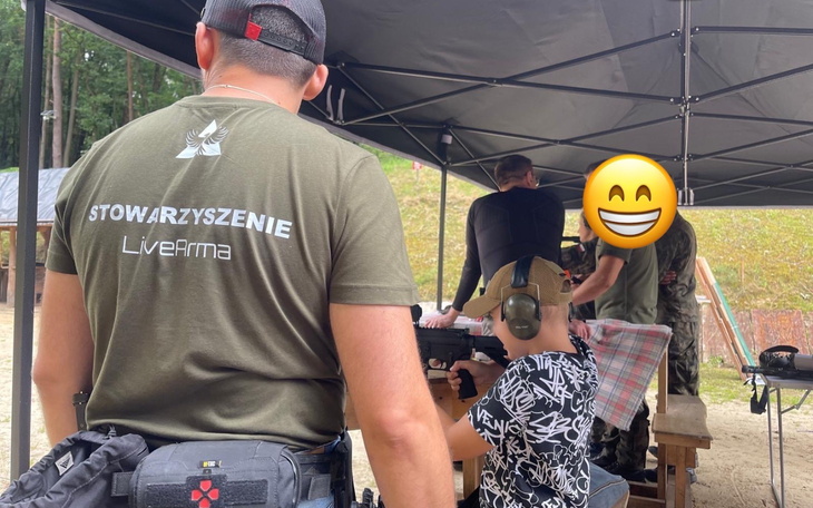 Osoby na strzelnicy, jedna z nich nosi słuchawki ochronne.