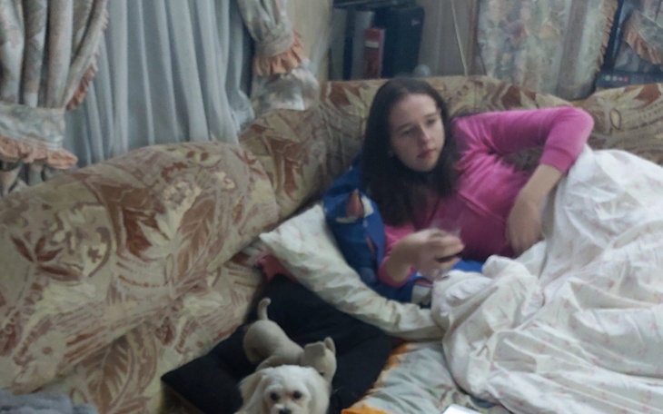 Dziewczyna leżąca na kanapie z psem obok, w domowym otoczeniu.