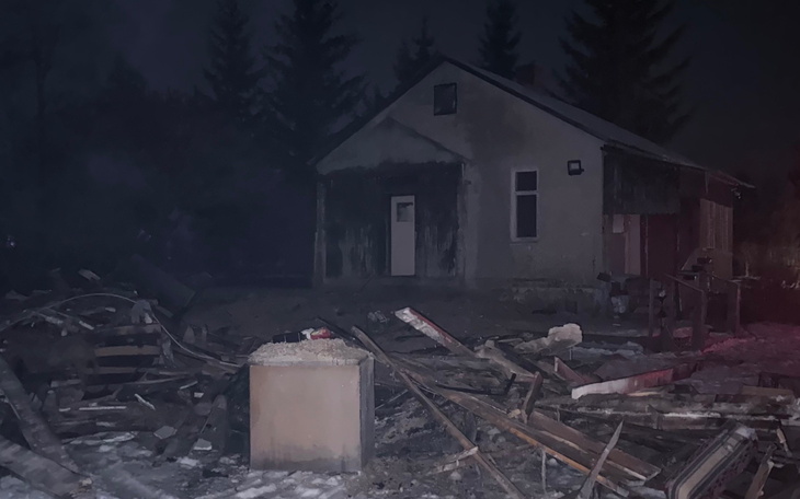 Zniszczony dom w nocy, otoczenie wygląda na opustoszałe.